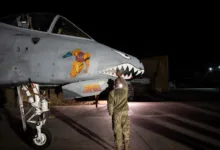A-10 Warthog with 'Metroid' nose art being inspected at night on the flight line.