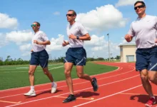 Three Air Force members running on a track in athletic gear.