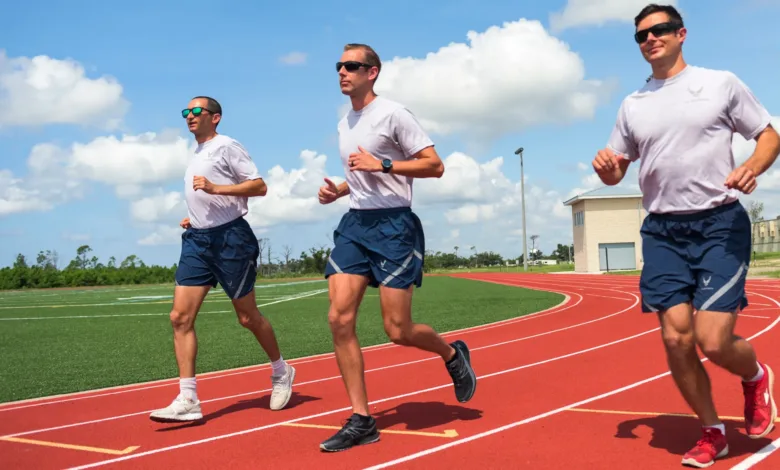 Three Air Force members running on a track in athletic gear.