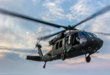Black Hawk helicopter in flight against a cloudy sky.