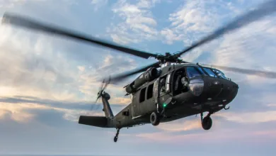 Black Hawk helicopter in flight against a cloudy sky.