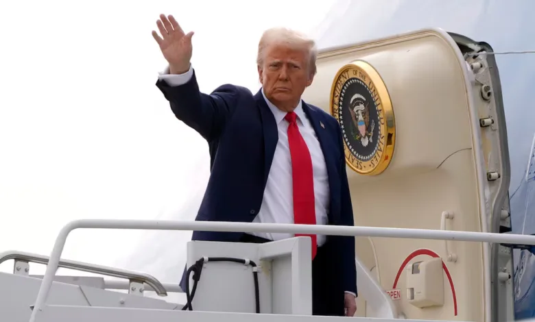 Donald Trump waves from Air Force One stairs, wearing a suit and red tie.