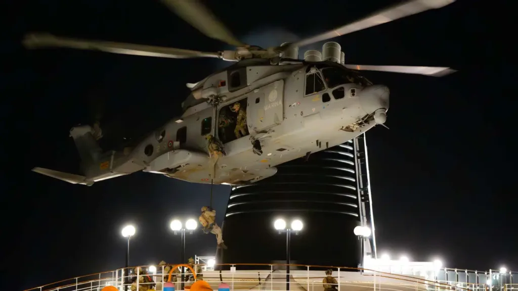 Italian Navy helicopter fast-roping exercise at night, soldiers descending ropes.