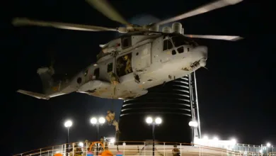 Italian Navy helicopter fast-roping exercise at night, soldiers descending ropes.