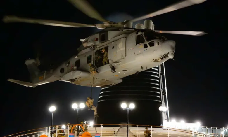 Italian Navy helicopter fast-roping exercise at night, soldiers descending ropes.