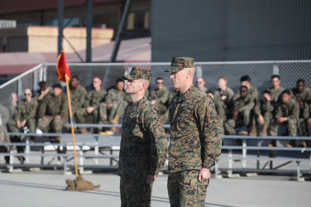 Two Marines stand at attention during a change of command ceremony.