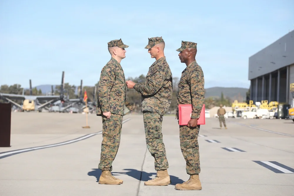 Marines at HMLA-169 change of command ceremony on airfield. Military personnel in camouflage uniforms.
