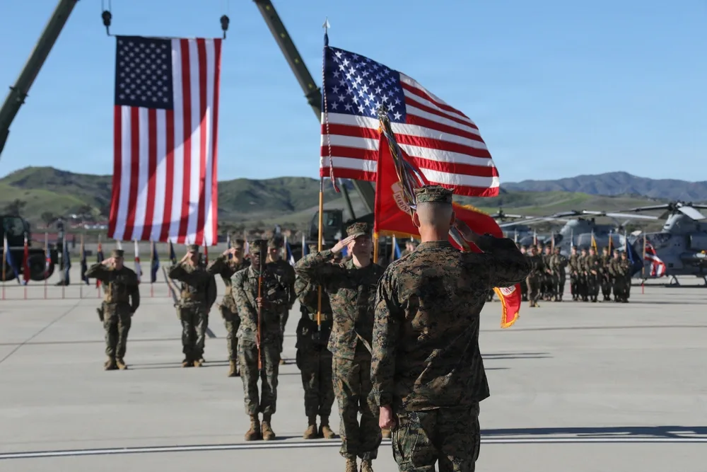Marines salute during HMLA-169 change of command ceremony with American flags.