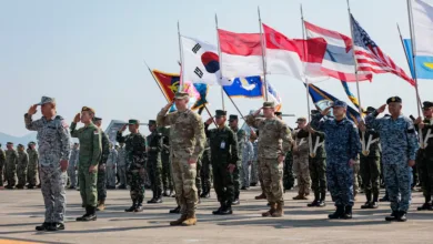 Multinational military members salute flags at a joint exercise event.