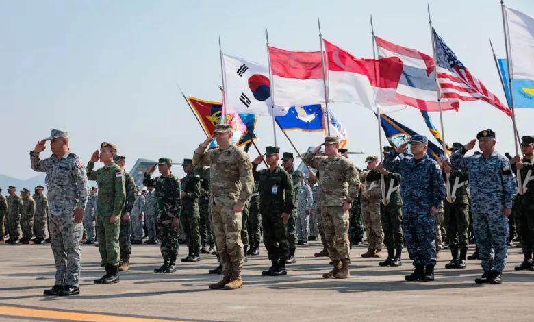 Multinational military members salute flags at a joint exercise event.