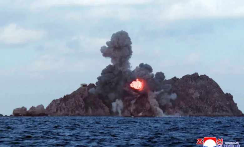 North Korea military exercise shows explosion on island target, smoke plumes.