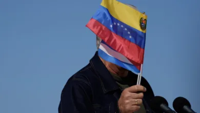 Person holding Venezuelan flag in front of face at podium.