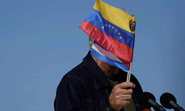 Person holding Venezuelan flag in front of face at podium.