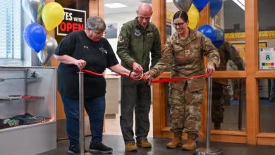 Ribbon cutting ceremony with three people and balloons at an opening.