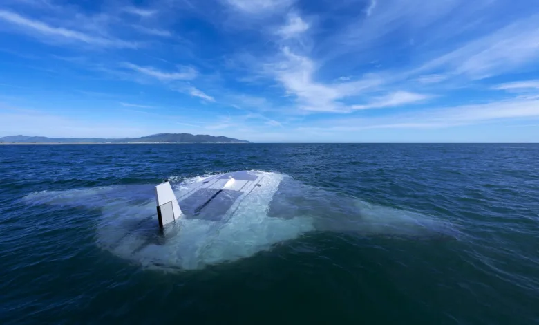 Partially submerged stealth boat in ocean, blue sky above.