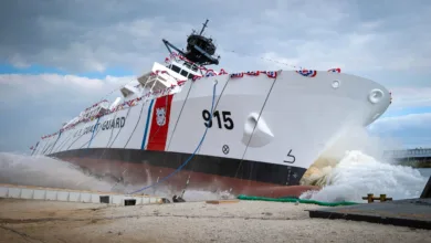 US Coast Guard cutter launching, hull number 915, with water splashing.