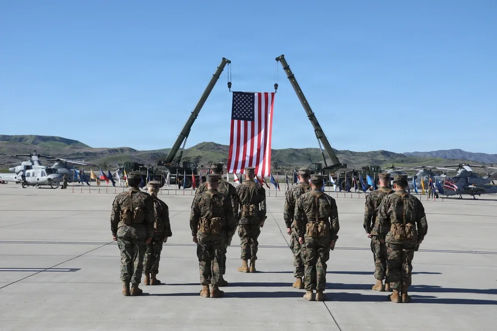 US Marines stand at attention before a large American flag ceremony.