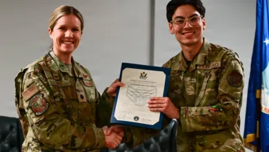 Air Force officer shaking hands, presenting certificate to Airman Palomino.