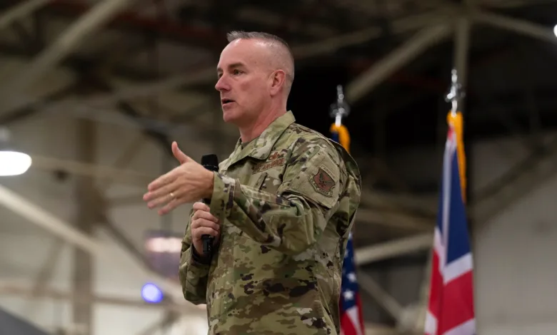 Air Force officer speaks at event, gesturing with hand and holding a microphone.