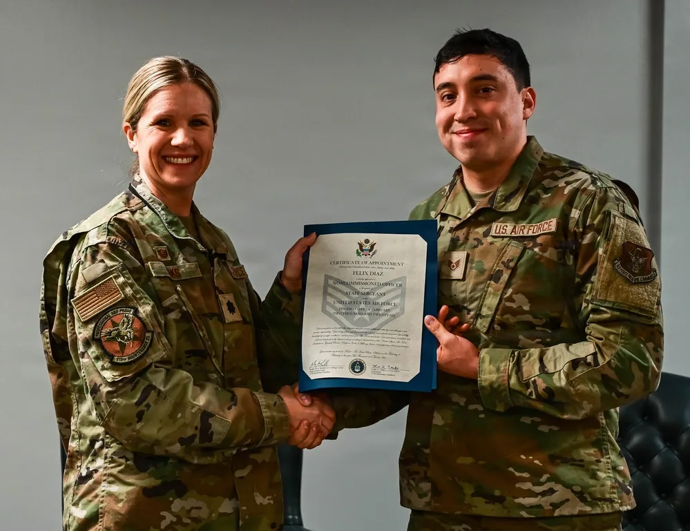 Air Force promotion: Felix Diaz receives certificate from superior, smiling.