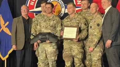 Army aviation team receiving award, standing with presenters in uniform.