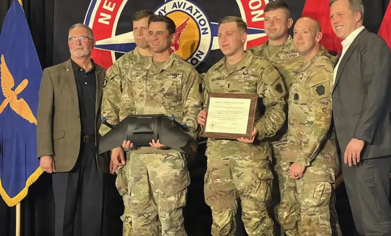 Army aviation team receiving award, standing with presenters in uniform.