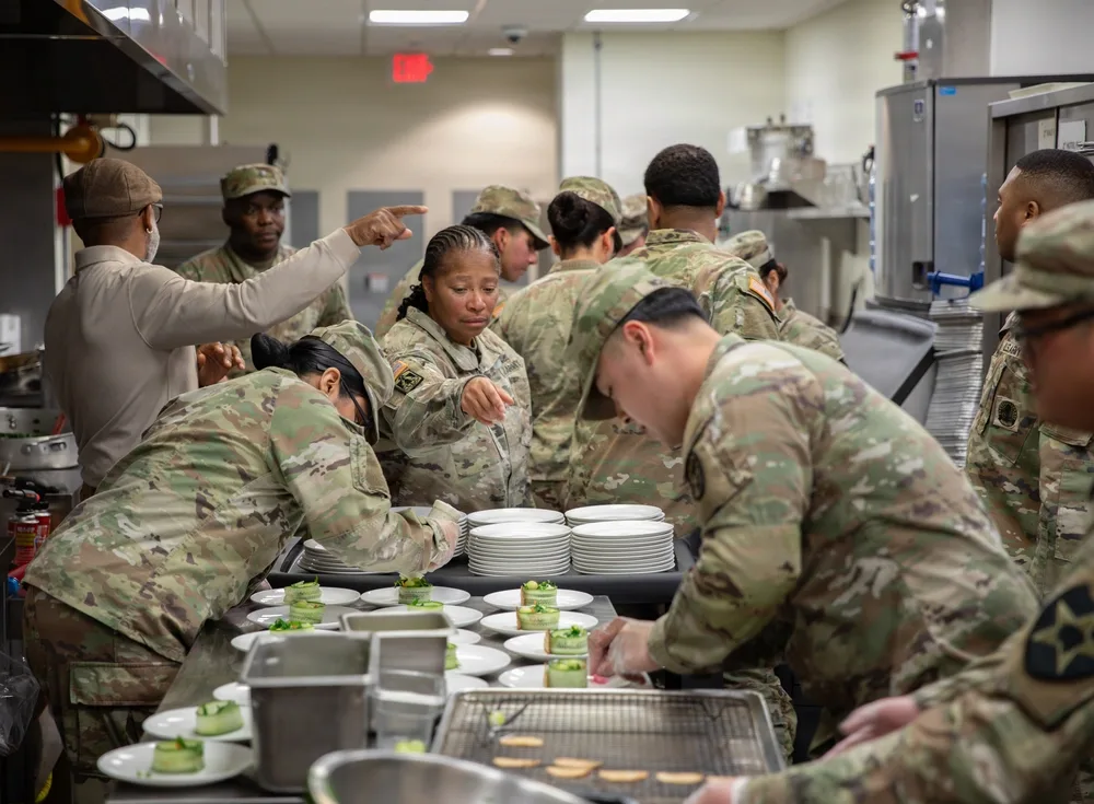 Army cooks preparing food in a kitchen, plates with appetizers.