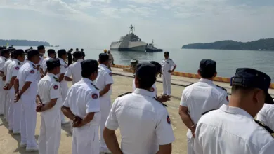 Cambodian naval officers stand at attention as a ship arrives at port.