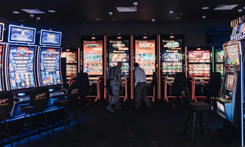 Casino interior with rows of slot machines and two people walking.