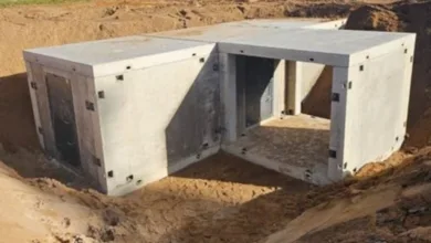 Concrete storm shelter partially buried in the ground, showing doorway.