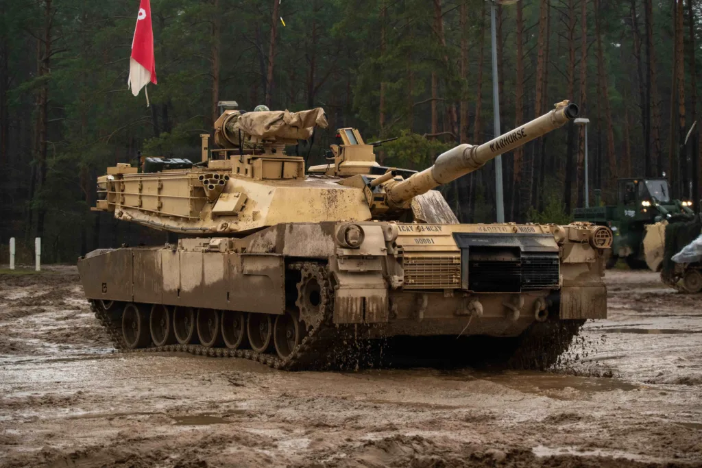 M1 Abrams tank "WARHORSE" in muddy field during winter training in Poland.