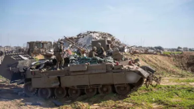 Israeli soldiers on tank amidst rubble in Gaza.