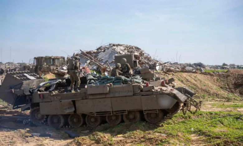 Israeli soldiers on tank amidst rubble in Gaza.