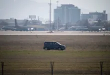 KC-135 Stratotankers on airfield with service vehicle and city buildings in background.