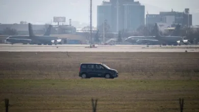 KC-135 Stratotankers on airfield with service vehicle and city buildings in background.