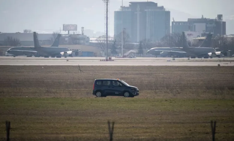KC-135 Stratotankers on airfield with service vehicle and city buildings in background.