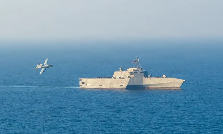 Littoral Combat Ship with A-10 Thunderbolt II flying nearby on the ocean.