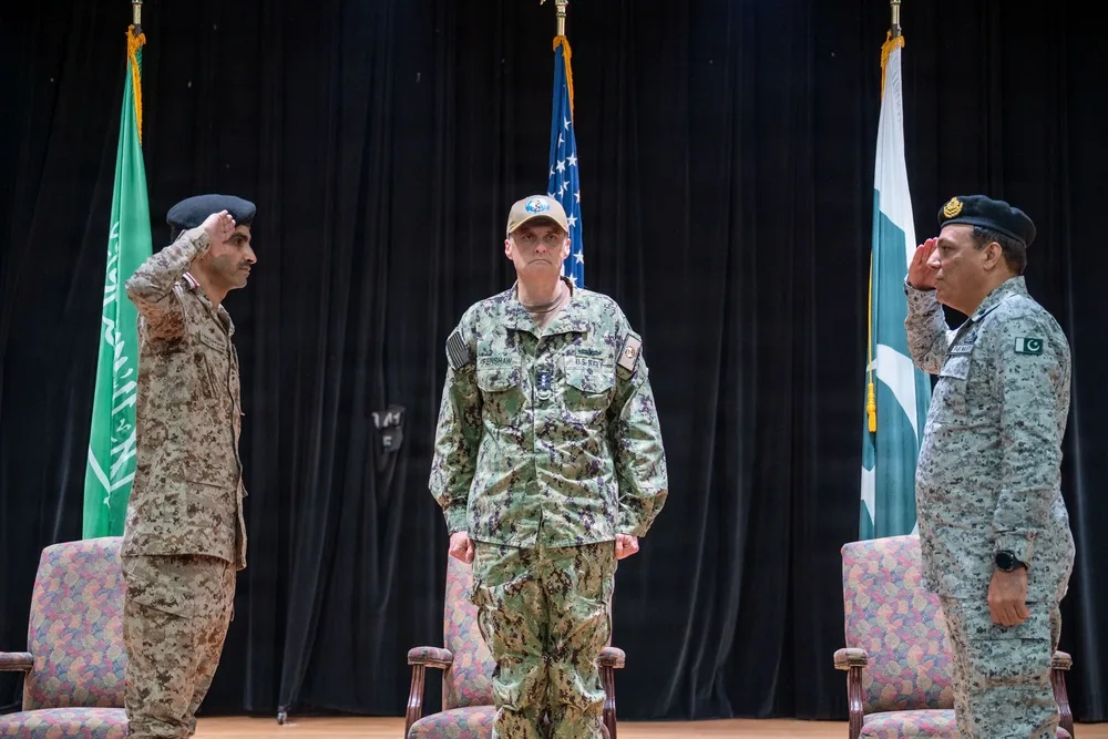 Three military officers salute during a Combined Maritime Forces ceremony.