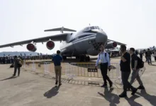 Large military transport aircraft on display at an airshow with people walking by.