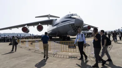 Large military transport aircraft on display at an airshow with people walking by.