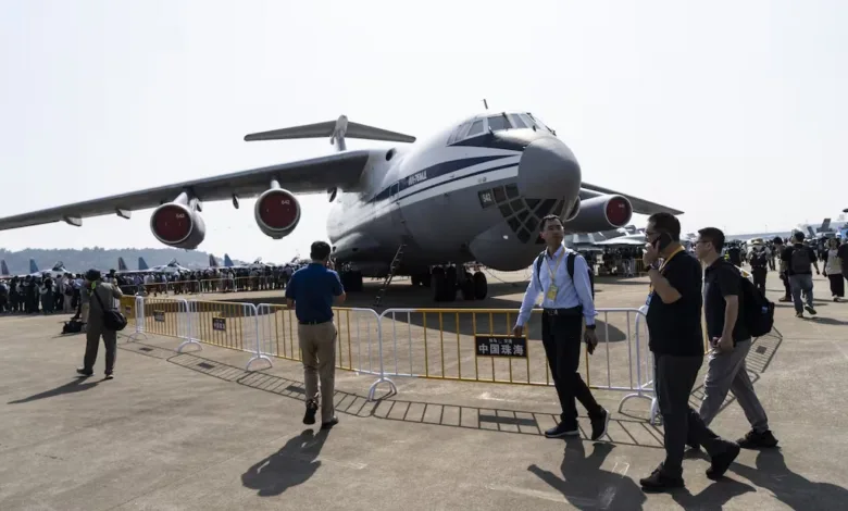 Large military transport aircraft on display at an airshow with people walking by.