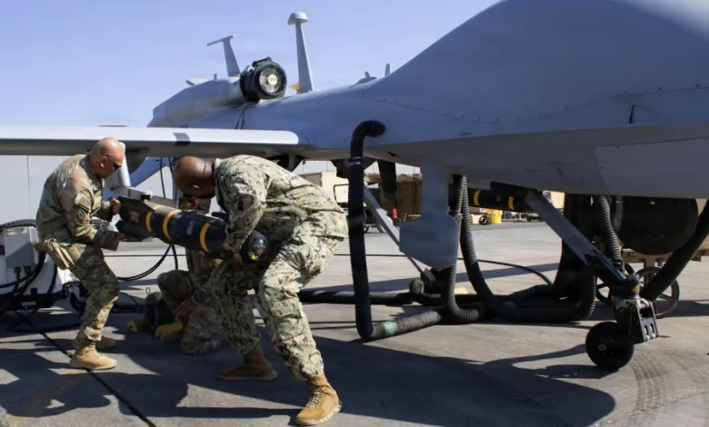 US Navy personnel loading missile onto MQ-9 Reaper drone aircraft.