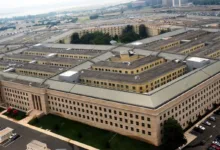 Aerial view of The Pentagon building in Arlington, Virginia, with parking lots and surrounding greenery visible.