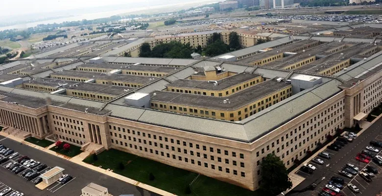 Aerial view of The Pentagon building in Arlington, Virginia, with parking lots and surrounding greenery visible.