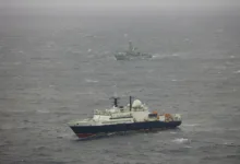 Russian research vessel Yantar and British frigate HMS Northumberland at sea on a gray, overcast day.