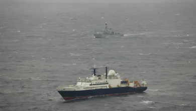 Russian research vessel Yantar and British frigate HMS Northumberland at sea on a gray, overcast day.