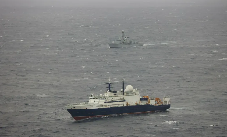 Russian research vessel Yantar and British frigate HMS Northumberland at sea on a gray, overcast day.