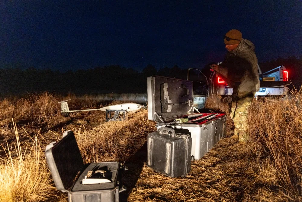 Soldier prepares drone equipment at night during Ghost Rig exercise.