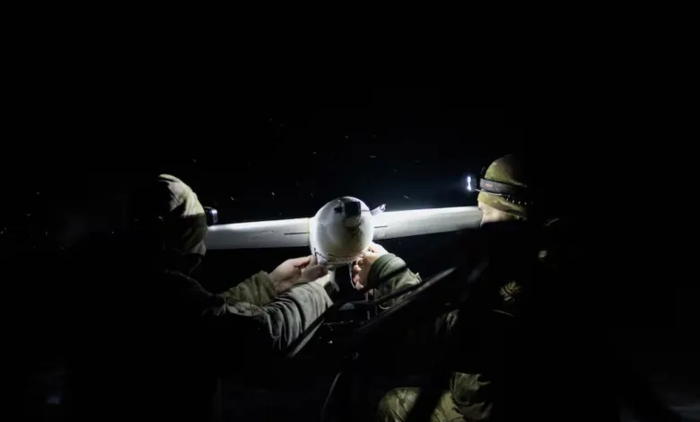 Soldiers preparing a drone for night mission, wearing headlamps in the dark.