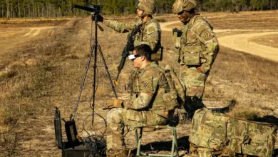 Soldiers using drone technology in field training exercise with tripod and gear.